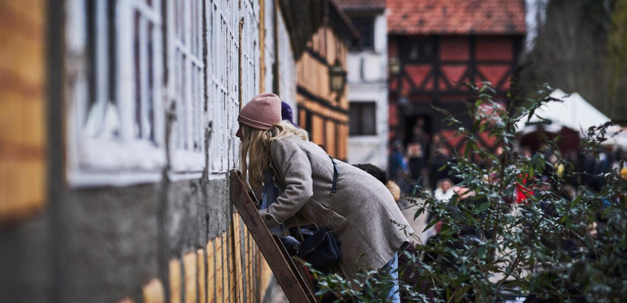 Pige kigger ind af vindue i Den Gamle By